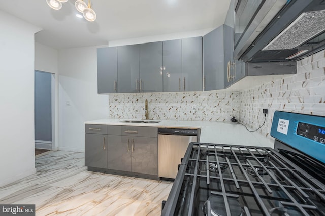 kitchen featuring gray cabinetry, wall chimney range hood, sink, decorative backsplash, and stainless steel appliances