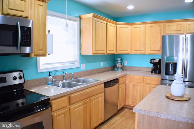 kitchen featuring sink, light brown cabinets, hanging light fixtures, light hardwood / wood-style flooring, and appliances with stainless steel finishes