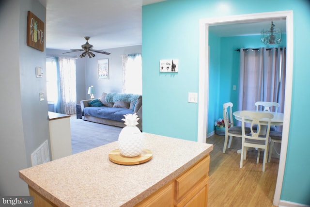 kitchen featuring light brown cabinetry, light hardwood / wood-style floors, and ceiling fan with notable chandelier