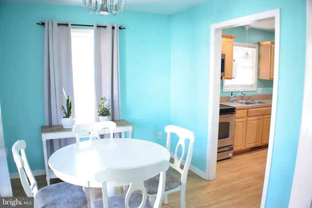 dining area featuring a notable chandelier, light hardwood / wood-style floors, and sink