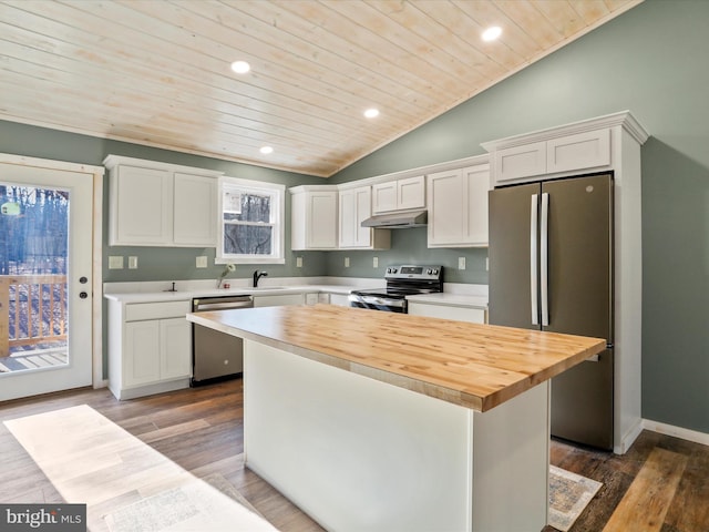 kitchen with wood counters, appliances with stainless steel finishes, vaulted ceiling, white cabinets, and a center island