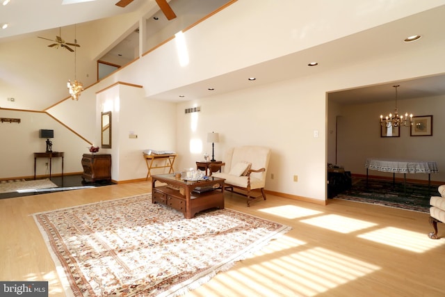 living area featuring ceiling fan with notable chandelier, a towering ceiling, and light wood-type flooring