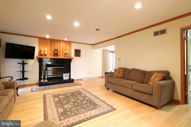 living room with crown molding, a high end fireplace, and light hardwood / wood-style floors