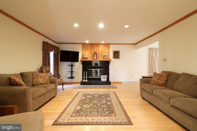 living room with crown molding, a high end fireplace, and light wood-type flooring