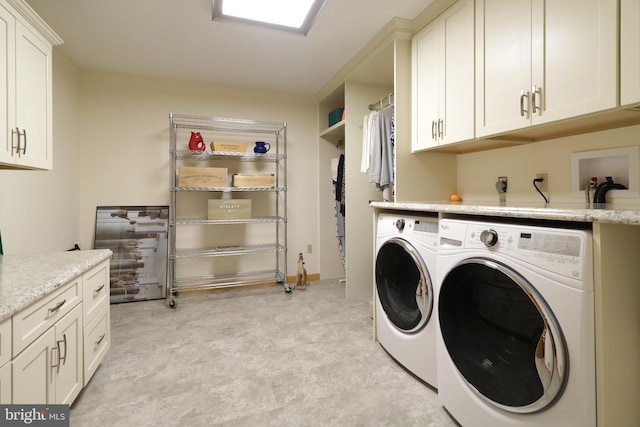 clothes washing area with cabinets and washer and dryer