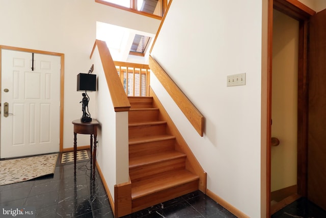 entrance foyer with dark tile patterned flooring and a skylight