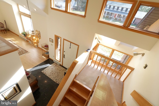 staircase featuring a high ceiling, plenty of natural light, hardwood / wood-style flooring, and a chandelier