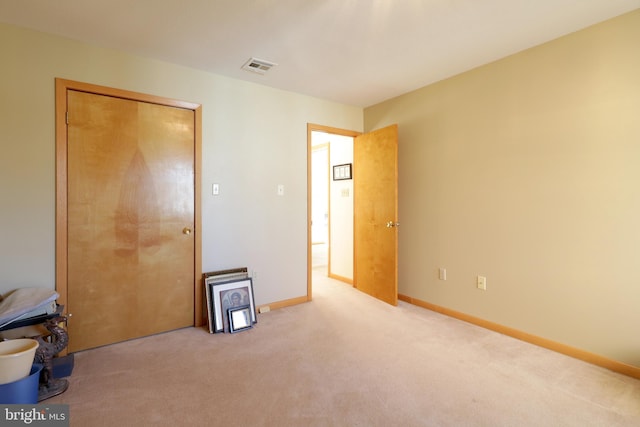 unfurnished bedroom with light colored carpet and a closet