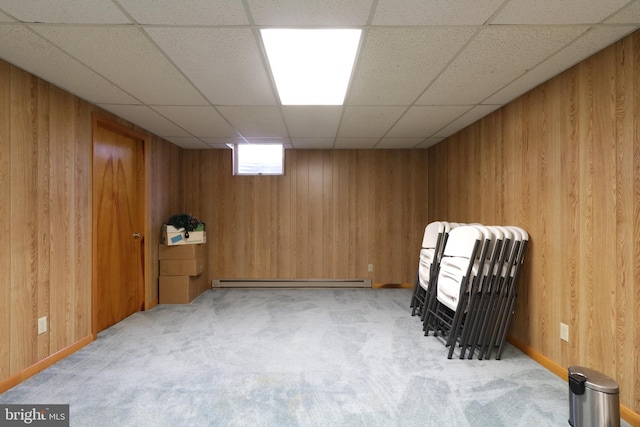 interior space featuring a paneled ceiling, wooden walls, light colored carpet, and baseboard heating