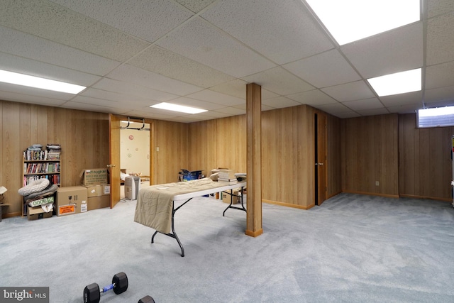 playroom with carpet, a drop ceiling, and wood walls