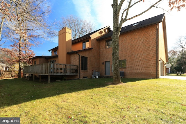 back of property featuring a wooden deck, a garage, a lawn, and central air condition unit