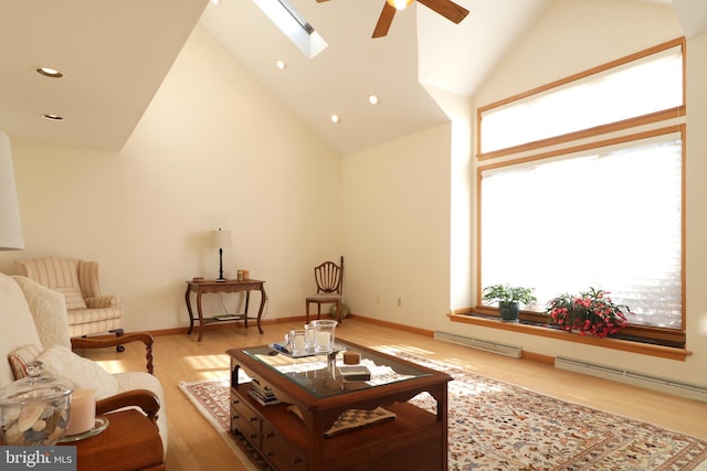 living room featuring ceiling fan, a skylight, high vaulted ceiling, and light hardwood / wood-style flooring