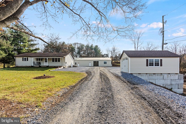 ranch-style home featuring covered porch, a garage, an outdoor structure, and a front lawn