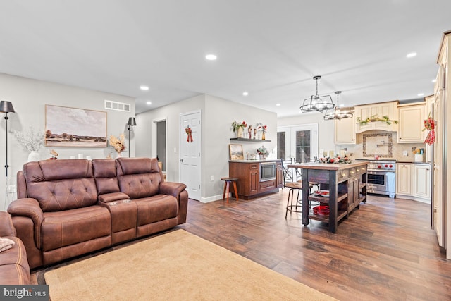 living room with dark hardwood / wood-style flooring, french doors, and an inviting chandelier