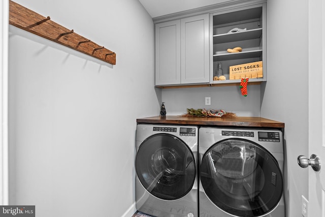 washroom with washer and dryer and cabinets