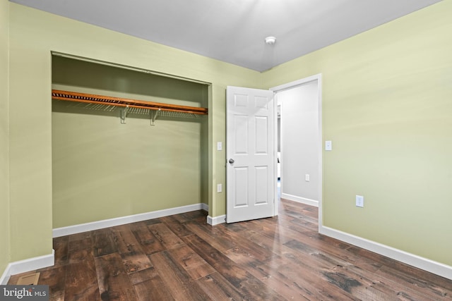 unfurnished bedroom featuring a closet and dark wood-type flooring