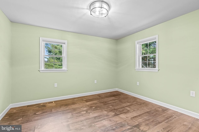 unfurnished room with hardwood / wood-style flooring and a healthy amount of sunlight