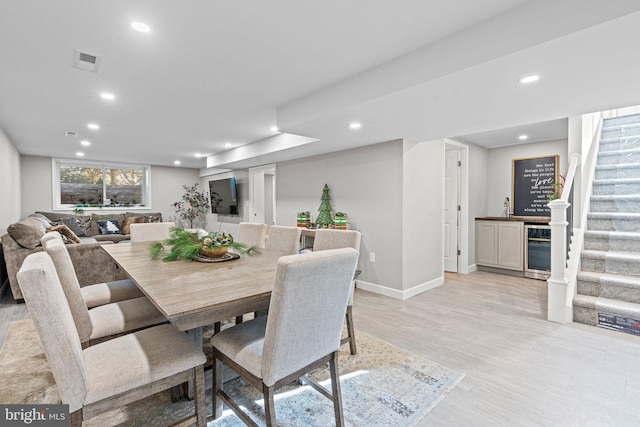 dining space with wine cooler, light hardwood / wood-style flooring, and indoor bar