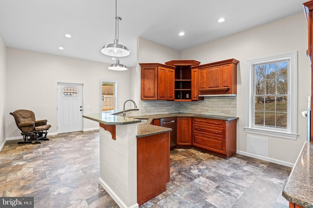 kitchen featuring sink, hanging light fixtures, dark stone countertops, tasteful backsplash, and kitchen peninsula