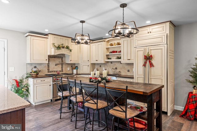 kitchen with tasteful backsplash, cream cabinets, dark hardwood / wood-style floors, and high end stainless steel range