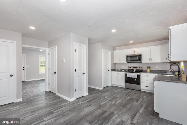 kitchen with white cabinets, stainless steel appliances, dark wood-style floors, a sink, and recessed lighting