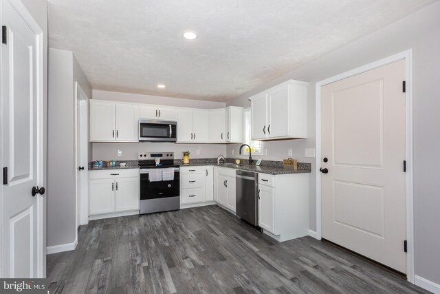 kitchen with dark wood finished floors, white cabinetry, baseboards, and stainless steel appliances