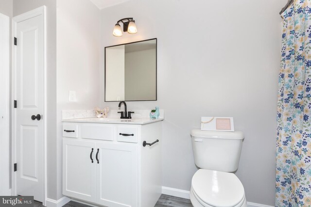 full bath featuring baseboards, curtained shower, vanity, and toilet