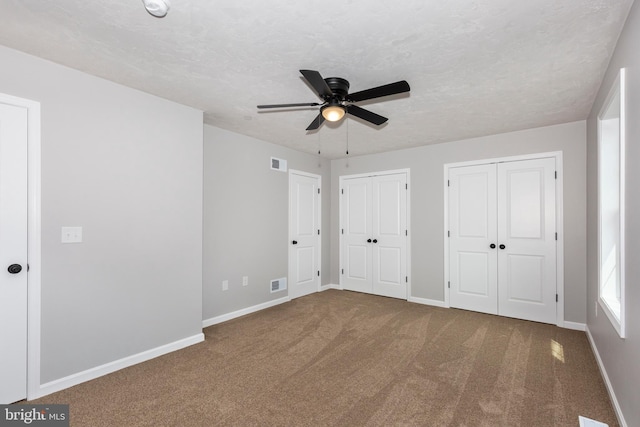 unfurnished bedroom with two closets, carpet floors, and visible vents