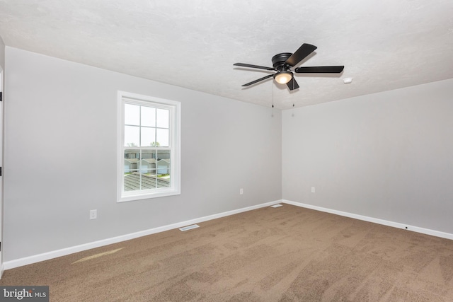 unfurnished room with carpet, visible vents, baseboards, and ceiling fan