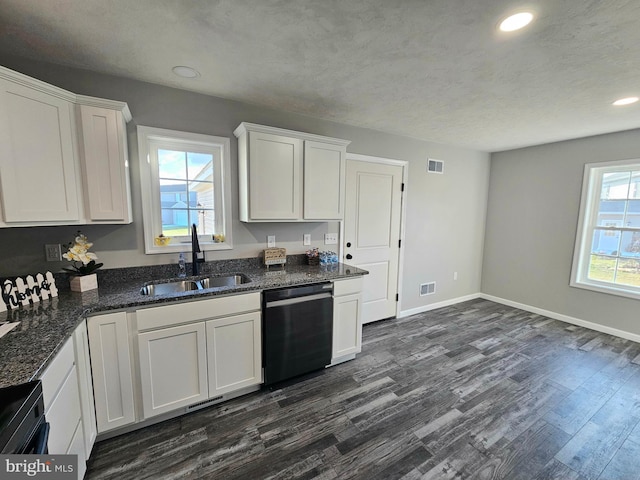 kitchen featuring stainless steel dishwasher, dark wood-type flooring, sink, dark stone countertops, and white cabinetry