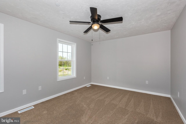 unfurnished room featuring dark carpet, visible vents, and baseboards