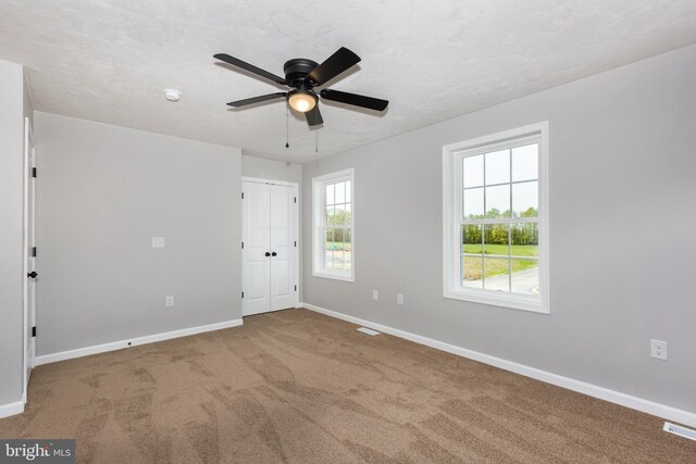 unfurnished bedroom featuring visible vents, baseboards, a ceiling fan, a closet, and carpet floors