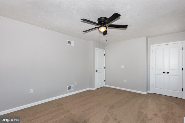 unfurnished bedroom featuring a textured ceiling, carpet floors, visible vents, and baseboards