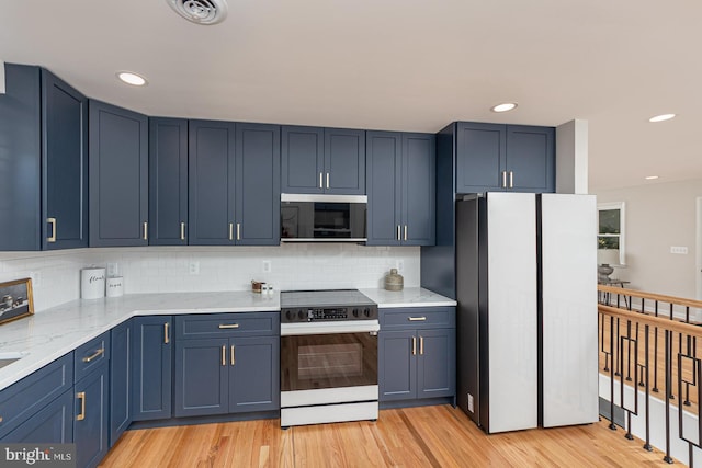 kitchen featuring decorative backsplash, light wood-type flooring, blue cabinets, white fridge, and range with electric stovetop