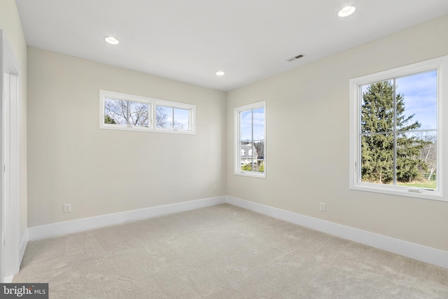 spare room featuring light colored carpet and a healthy amount of sunlight