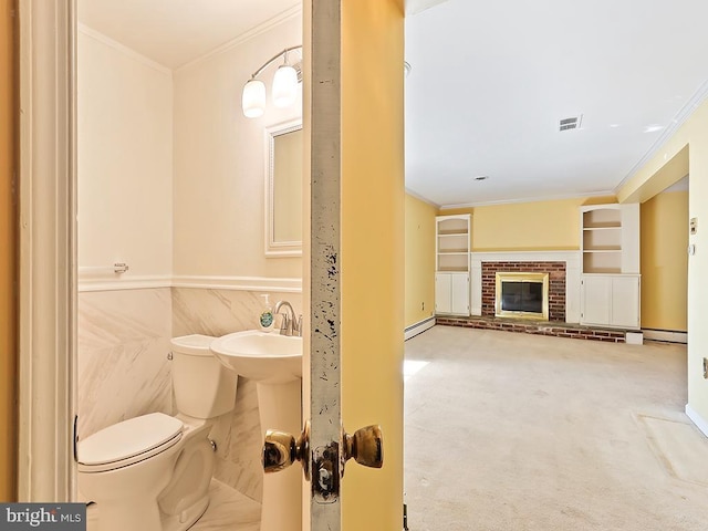 bathroom featuring a baseboard heating unit, a brick fireplace, toilet, built in features, and ornamental molding