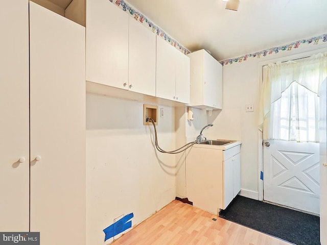 laundry room featuring sink, cabinets, and light hardwood / wood-style floors