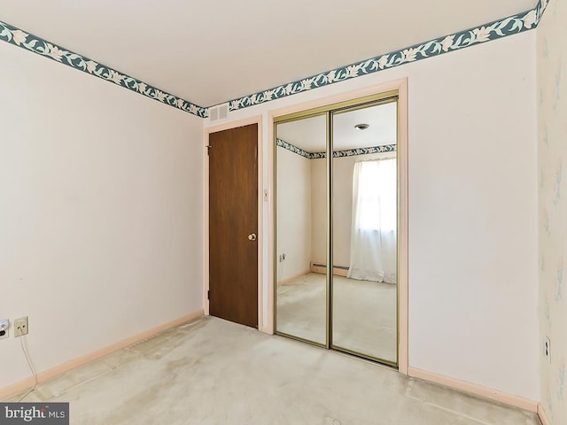 unfurnished bedroom with baseboard heating and a closet