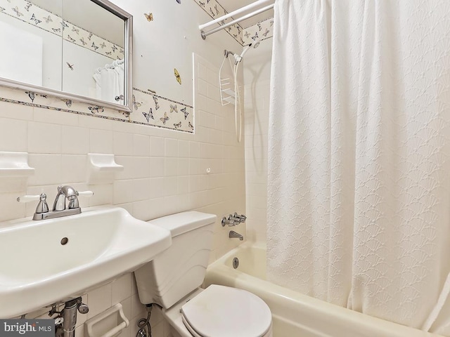 full bathroom featuring sink, shower / bath combination with curtain, tile walls, and toilet