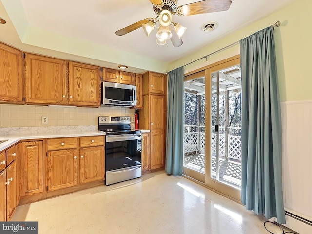 kitchen with baseboard heating, decorative backsplash, ceiling fan, and appliances with stainless steel finishes