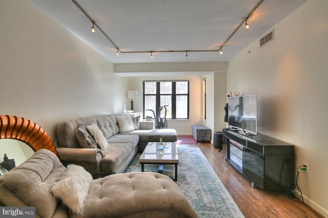 living room featuring a textured ceiling, wood-type flooring, and rail lighting