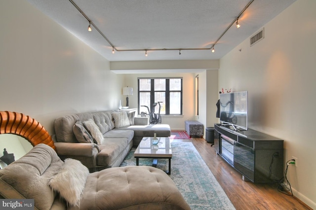 living room with hardwood / wood-style flooring, rail lighting, and a textured ceiling