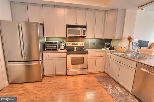 kitchen featuring backsplash, track lighting, sink, light hardwood / wood-style flooring, and stainless steel appliances