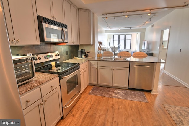 400 Massachusetts Ave NW Unit 423, Washington, DC 20001 - kitchen featuring stainless steel appliances, a peninsula, light wood finished floors, open floor plan, and light stone counters