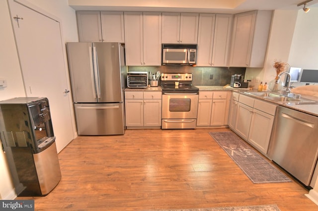 kitchen featuring decorative backsplash, light hardwood / wood-style floors, sink, and appliances with stainless steel finishes