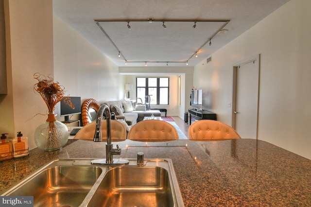 kitchen featuring dark stone countertops, sink, and track lighting