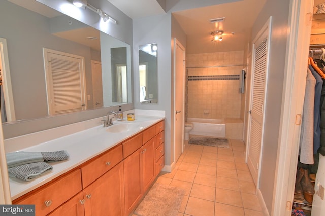 full bathroom with tiled shower / bath, tile patterned flooring, vanity, and toilet