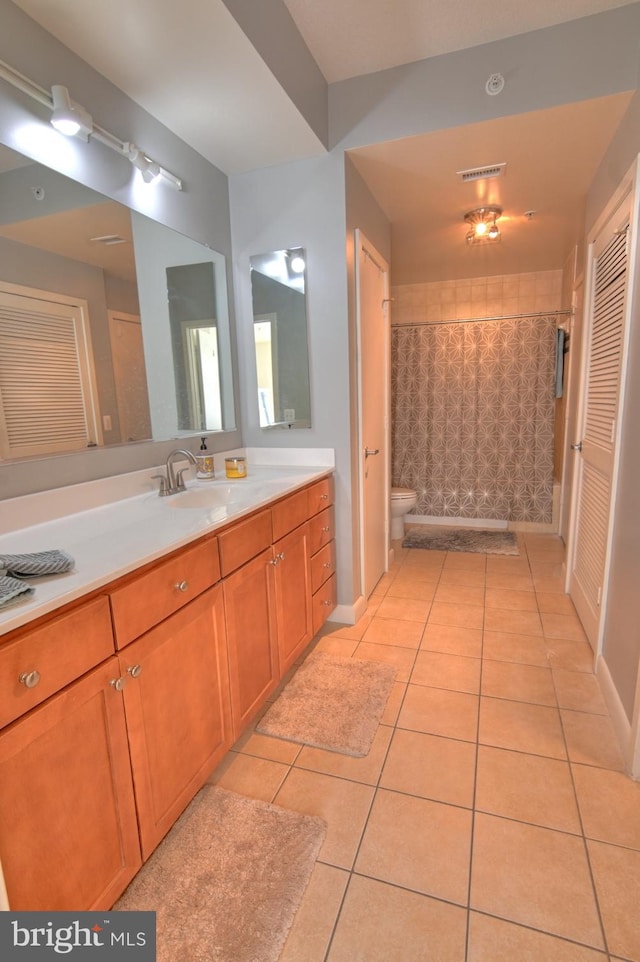 bathroom with tile patterned floors, walk in shower, vanity, and toilet