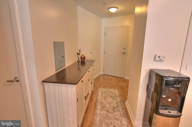 hallway featuring electric panel and light hardwood / wood-style flooring