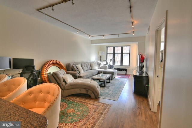 living room with a textured ceiling, light wood-type flooring, and track lighting